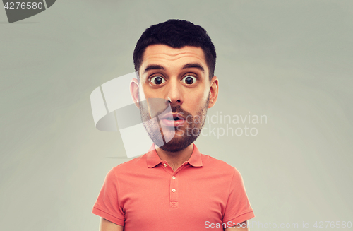 Image of surprised man in polo t-shirt over gray background