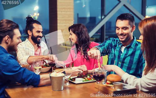 Image of friends eating and tasting food at restaurant