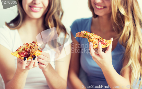 Image of happy friends or teen girls eating pizza at home