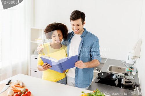 Image of happy couple with cooking book at home kitchen