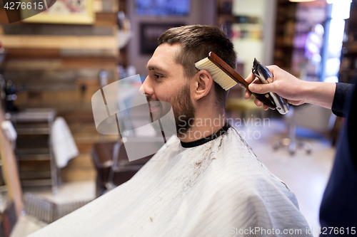 Image of man and barber with brush cleaning hair at salon