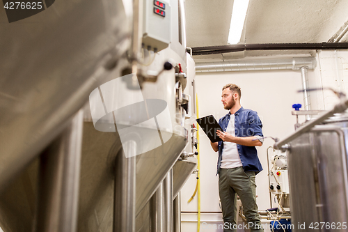 Image of man with clipboard at craft brewery or beer plant