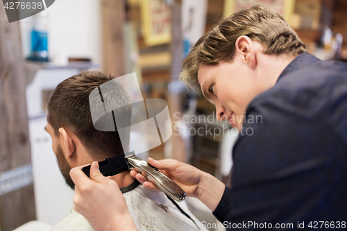 Image of man and barber with trimmer cutting hair at salon