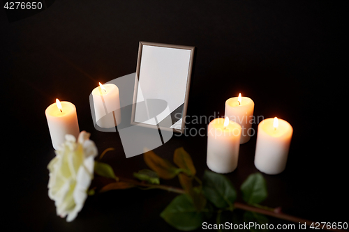 Image of photo frame with black ribbon, flower and candles