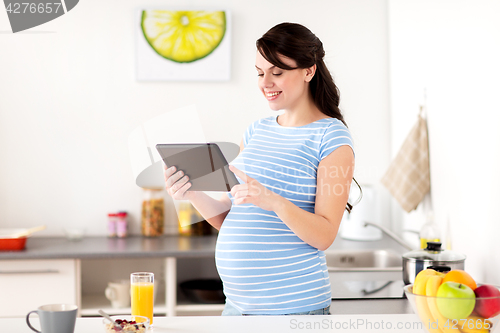 Image of pregnant woman with tablet pc eating at home