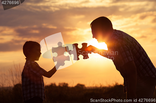 Image of Father and son playing at the park at the sunset time.