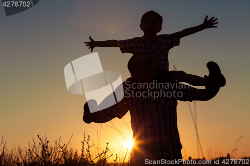 Image of Father and son playing at the park at the sunset time.