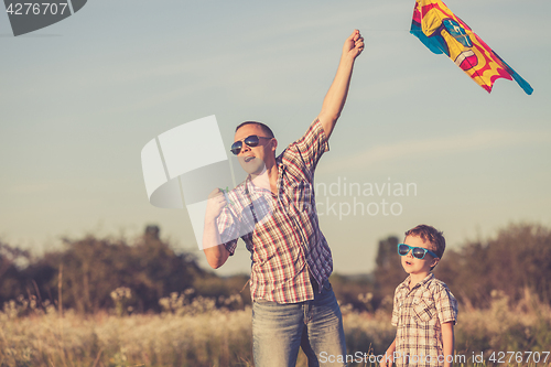 Image of Father and son playing at the park at the sunset time.