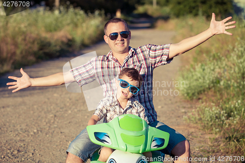 Image of Father and son playing on the road at the day time.
