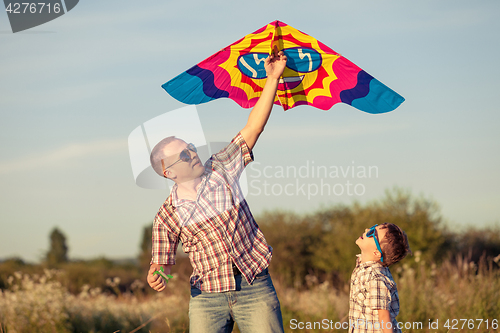 Image of Father and son playing at the park at the sunset time.