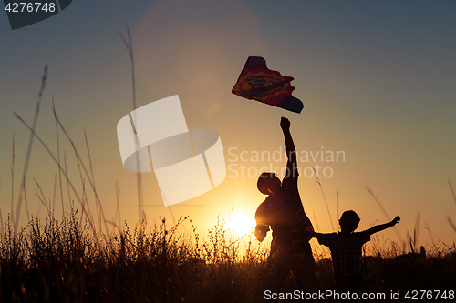 Image of Father and son playing at the park at the sunset time.