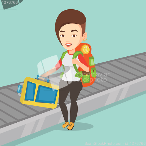 Image of Woman picking up suitcase on luggage conveyor belt