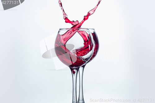 Image of Two wine glasses in toasting gesture with big splashing.