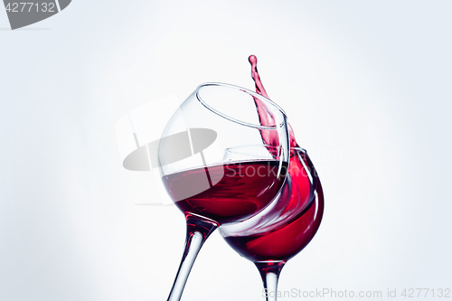 Image of Two wine glasses in toasting gesture with big splashing.