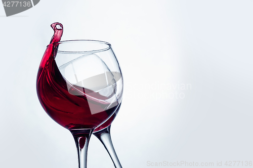 Image of Two wine glasses in toasting gesture with big splashing.