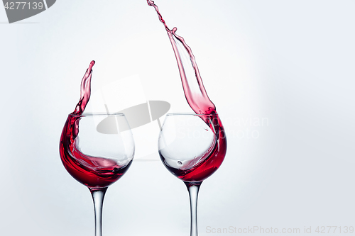 Image of Two wine glasses in toasting gesture with big splashing.