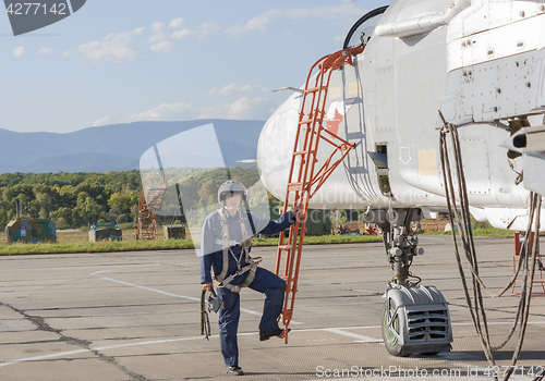 Image of Military pilot in helmet stands near jet plane