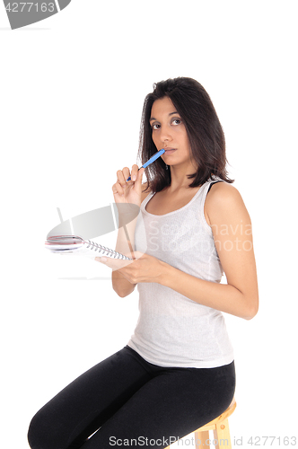 Image of Woman talking nots with pen in mouth.