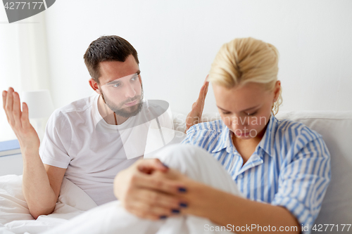 Image of unhappy couple having conflict in bed at home