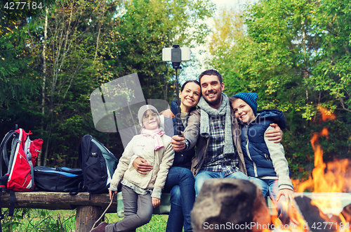 Image of family with smartphone taking selfie near campfire