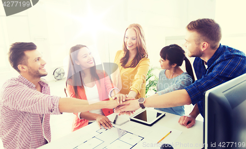 Image of creative team holding hands together  at office