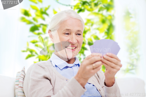 Image of happy senior woman playing cards at home