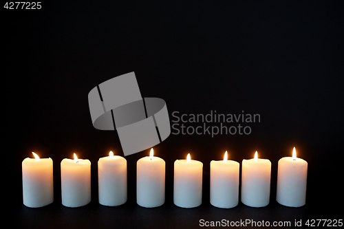 Image of candles burning in darkness over black background