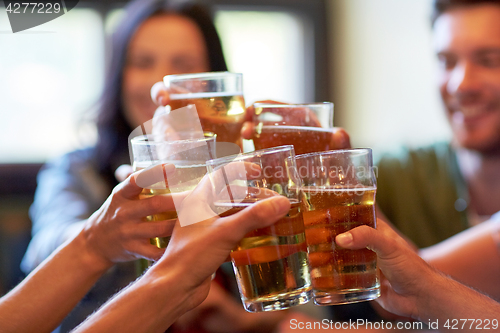 Image of happy friends drinking beer at bar or pub