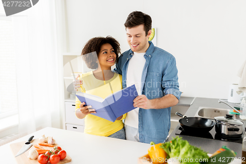 Image of happy couple with cooking book at home kitchen