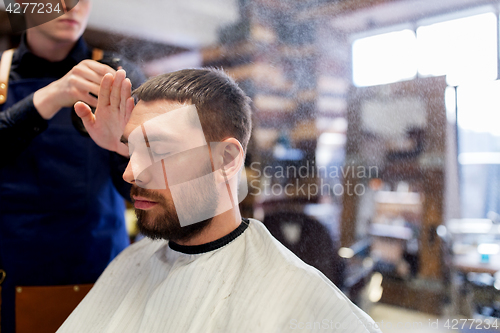 Image of barber applying styling spray to male hair