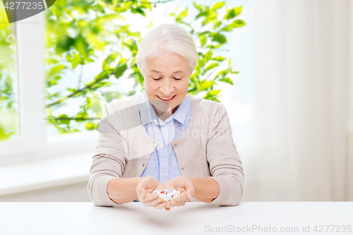 Image of happy senior woman with medicine at home