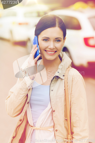 Image of smiling woman with smartphone over taxi in city