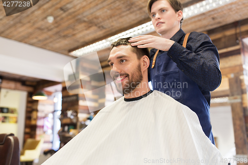 Image of man and barber styling hair at barbershop