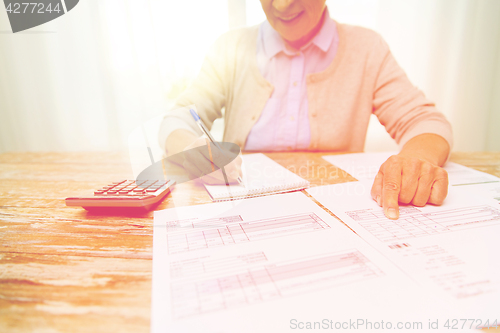 Image of senior woman with papers and calculator at home