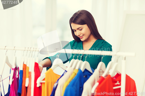 Image of happy woman choosing clothes at home wardrobe