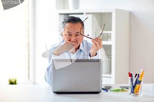 Image of businessman with eyeglasses and laptop at office