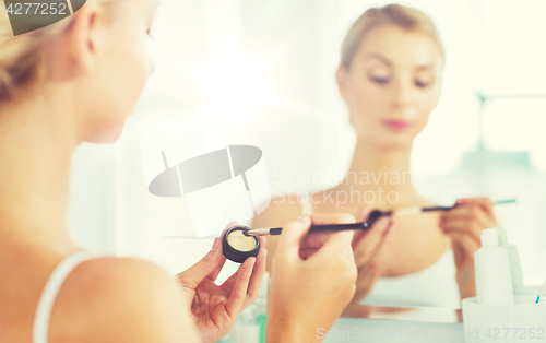 Image of woman with makeup brush and eyeshade at bathroom