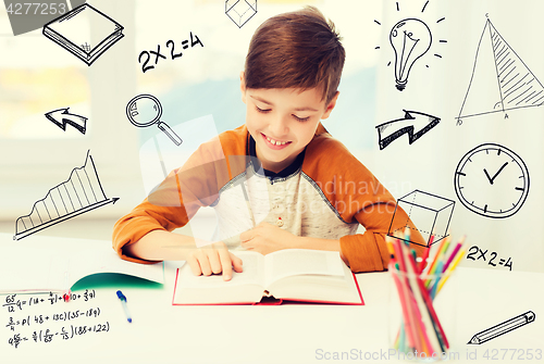 Image of smiling, student boy reading book at home