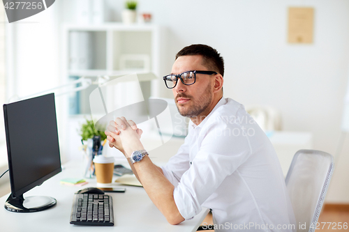 Image of businessman in glasses sitting at office computer