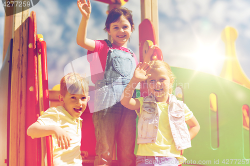 Image of group of happy kids waving hands on playground