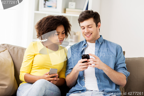 Image of happy couple with smartphones at home