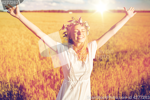 Image of happy young woman in flower wreath on cereal field