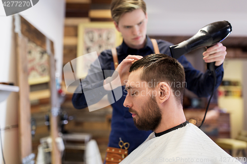 Image of barber with fan drying male hair at barbershop