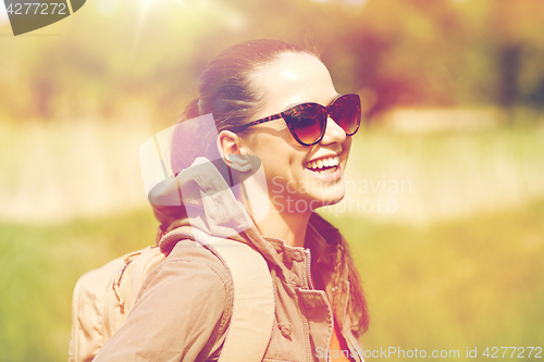 Image of happy young woman with backpack hiking outdoors