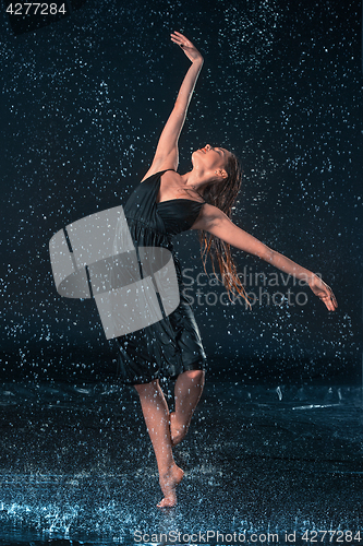 Image of The young beautiful modern dancer dancing under water drops