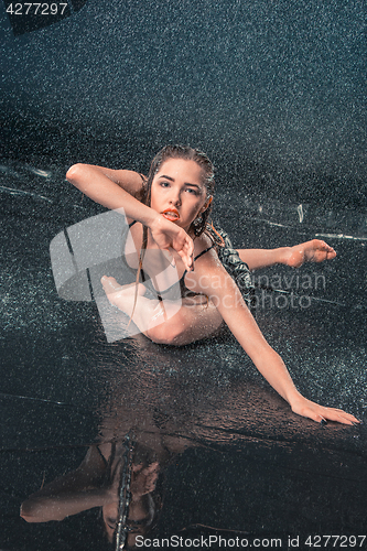 Image of The young beautiful modern dancer dancing under water drops