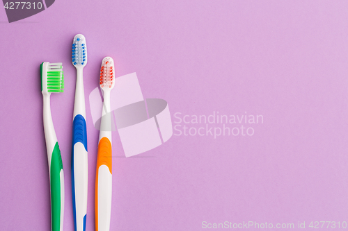 Image of Photo of three multi-colored toothbrushes