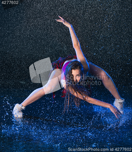 Image of The young beautiful modern dancer dancing under water drops