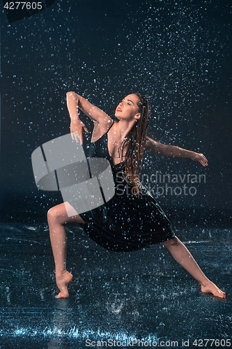 Image of The young beautiful modern dancer dancing under water drops