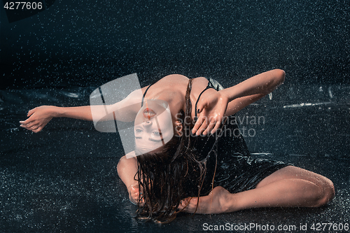 Image of The young beautiful modern dancer dancing under water drops